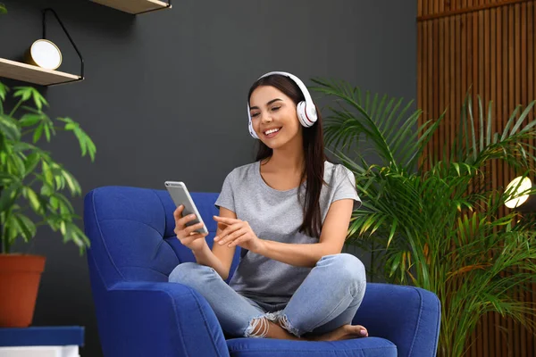Χαρούμενη γυναίκα που ακούει μουσική στην πολυθρόνα στο σπίτι. Φυτά εσωτερικού χώρου για μοντέρνα εσωτερική διακόσμηση — Φωτογραφία Αρχείου