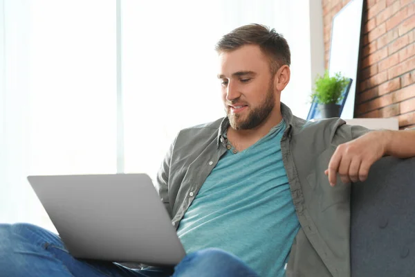 Hombre joven usando el ordenador portátil en la sala de estar — Foto de Stock