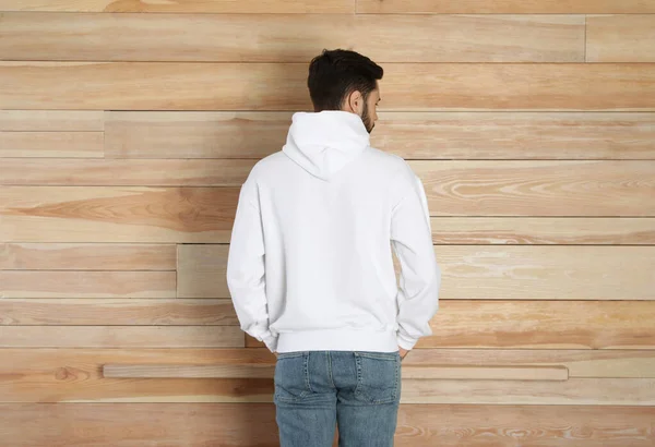 Young man in sweater at wooden wall. Mock up for design — Stock Photo, Image