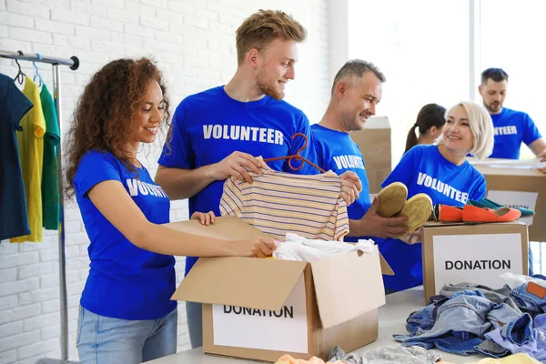 Equipe de voluntários coletando doações em caixas dentro de casa — Fotografia de Stock