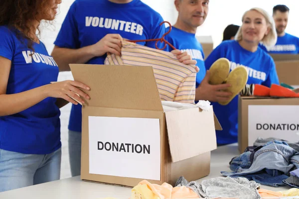 Equipe de voluntários coletando doações em caixas dentro de casa — Fotografia de Stock