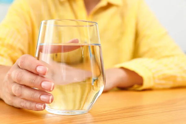 Femme tenant un verre d'eau à la table en bois, gros plan avec de l'espace pour le texte. Boisson rafraîchissante — Photo