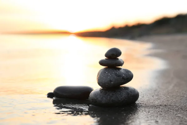 Pedras escuras na areia perto do mar ao pôr do sol, espaço para texto. Conceito Zen — Fotografia de Stock