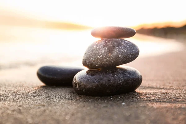 Темні камені на піску біля моря під час заходу сонця. концепція Zen — стокове фото