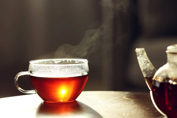 Teekanne und Tasse frischen heißen Tee auf Holztisch vor verschwommenem Hintergrund — Stockfoto