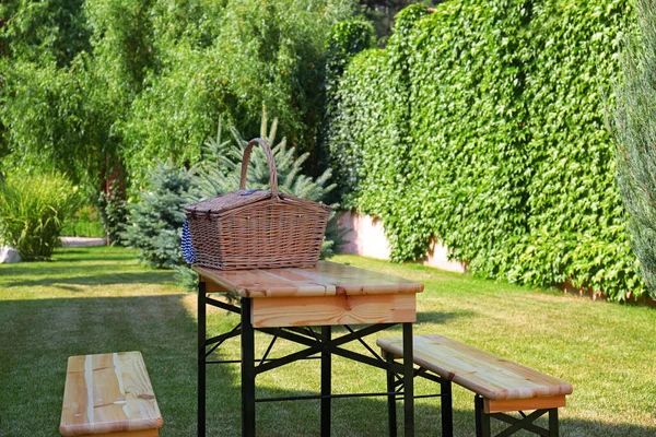 Kosz piknikowy na drewnianym stole w zielonym parku — Zdjęcie stockowe