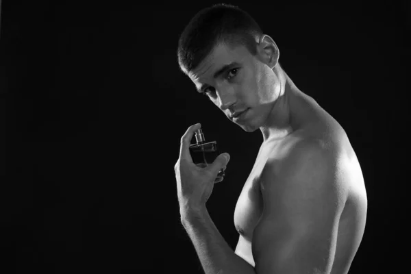Schöner junger Mann mit einer Flasche Parfüm, Schwarz-Weiß-Effekt — Stockfoto