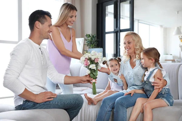 Szczęśliwa rodzina z małymi dziećmi gratuluje dojrzałej kobiecie w salonie — Zdjęcie stockowe