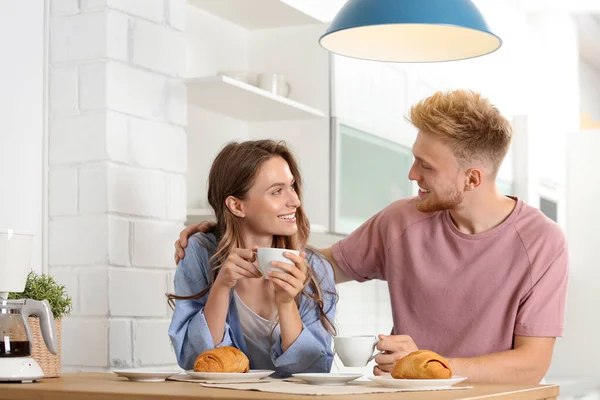 Feliz pareja joven desayunando en la mesa en la cocina — Foto de Stock