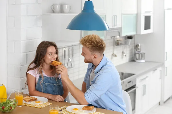 Feliz jovem casal tomando café da manhã à mesa na cozinha — Fotografia de Stock