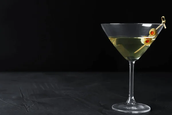 Glas av Classic Dry Martini med oliver på mörkt bord mot svart bakgrund. Plats för text — Stockfoto