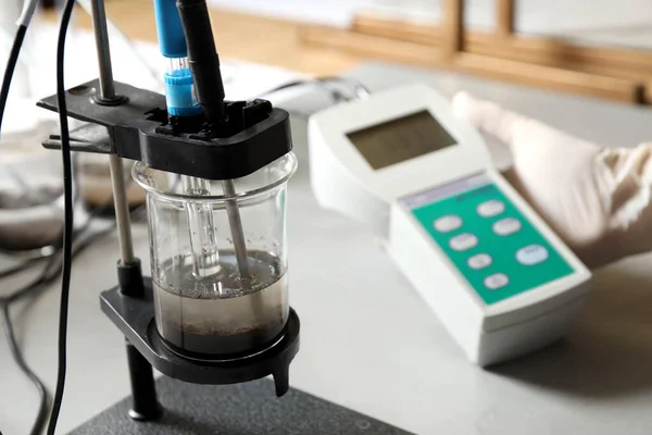 Wetenschapper meten van zuurgraad en pH van de grond bij tafel, close-up. Laboratoriumanalyse — Stockfoto