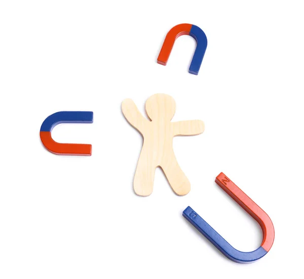 Red and blue horseshoe magnets with wooden human figure on white background, top view — Stock Fotó