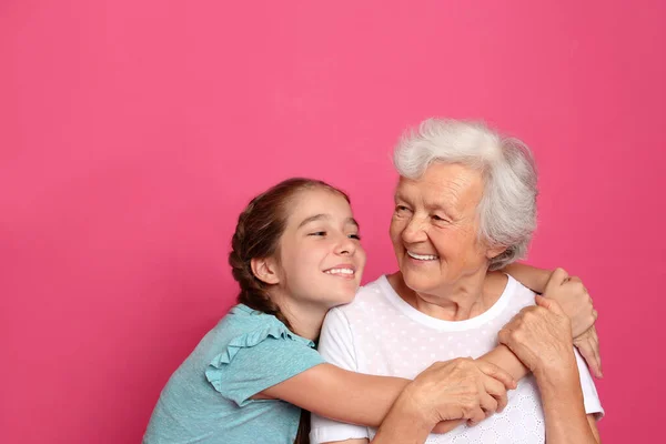 Fille mignonne étreignant sa grand-mère sur fond rose — Photo