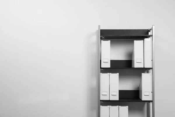 Unidade de prateleira com pastas perto da parede branca, espaço para texto — Fotografia de Stock