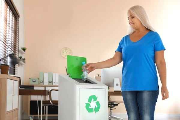 Mujer lanzando botella de plástico en la papelera de reciclaje en la oficina —  Fotos de Stock