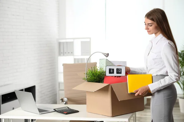 Joyeux jeune femme emballant des choses dans la boîte au bureau — Photo