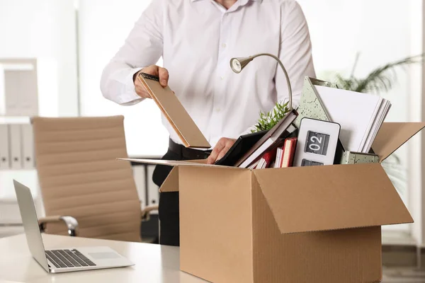 Молодой человек упаковывает вещи в коробку в офисе, крупным планом — стоковое фото