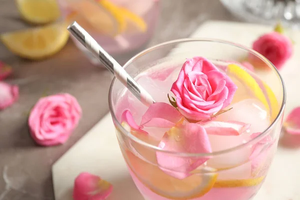 Glass of delicious refreshing drink with lemon and roses on table, closeup — Stock Photo, Image