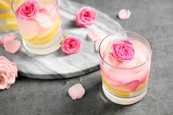 Deliciosa bebida refrescante con limón y rosas en la mesa gris —  Fotos de Stock