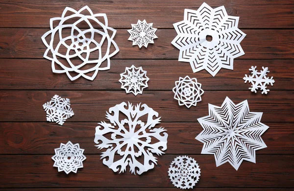 Composición plana con copos de nieve de papel sobre fondo de madera. Temporada de invierno —  Fotos de Stock