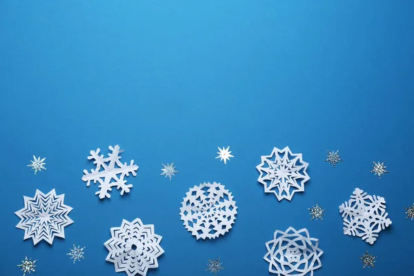 Flache Lagekomposition mit Papierschneeflocken auf blauem Hintergrund, Platz für Text. Wintersaison — Stockfoto