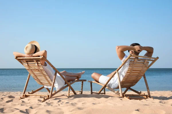 Jeune couple relaxant dans des chaises longues sur la plage — Photo