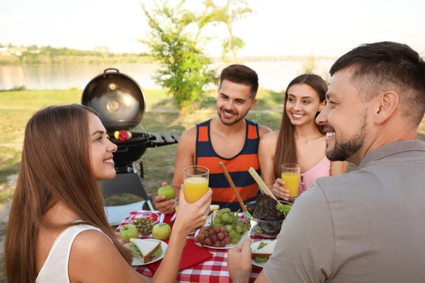 Giovani felici che fanno picnic a tavola nel parco — Foto Stock