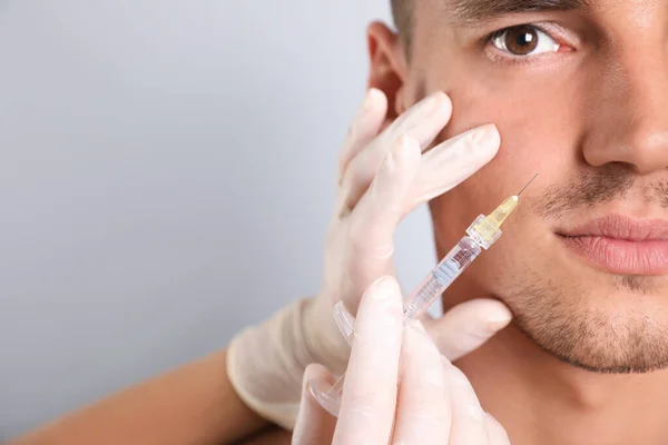 Man krijgt gezichts injectie op grijze achtergrond, close-up. Cosmetische chirurgie — Stockfoto
