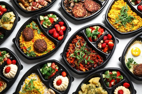 Lunchboxen met verschillende maaltijden op witte tafel, plat gelegd. Gezonde voedselverstrekking — Stockfoto