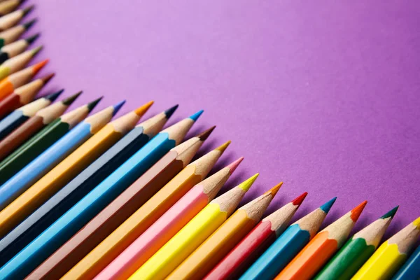 Состав с цветными карандашами на фиолетовом фоне — стоковое фото