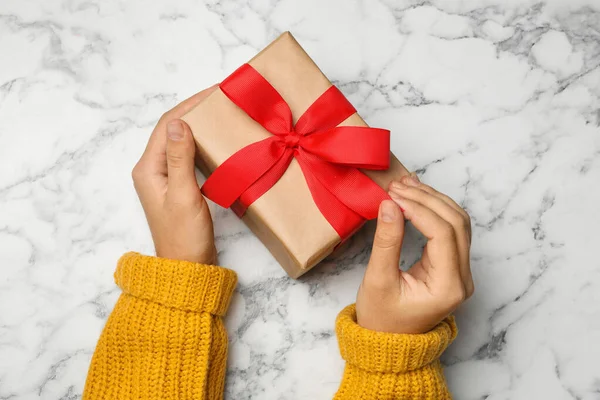 Jeune femme tenant cadeau de Noël sur fond de marbre blanc, vue de dessus — Photo