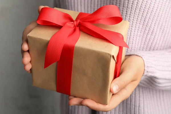 Young woman holding Christmas gift on light background, closeup — Stock Photo, Image