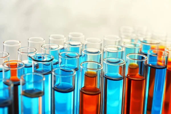 Muitos tubos de ensaio com diferentes amostras de líquido no fundo de cor, close-up — Fotografia de Stock