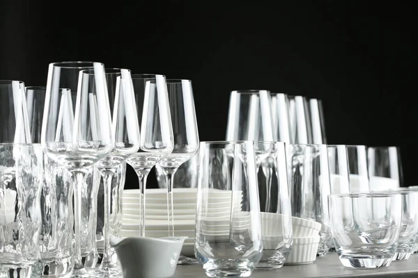 Set of empty glasses and dishware on table against black background — Stock Photo, Image