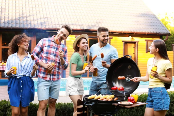 Grupa przyjaciół z grillowanymi kiełbaskami na grillu na świeżym powietrzu — Zdjęcie stockowe