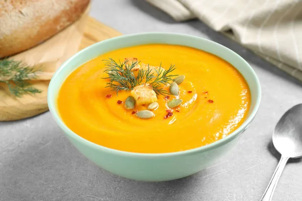 Delicious pumpkin soup in bowl on grey table — Stock Photo, Image