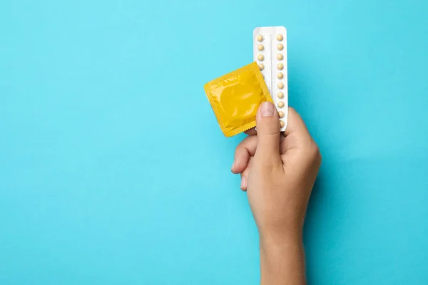 青い背景にコンドームと避妊薬を保持している女性, テキストのためのスペースを持つトップビュー.安全なセックス — ストック写真