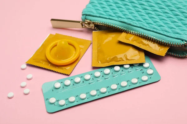 Sac à main avec préservatifs et pilules contraceptives sur fond rose. Sexe sans risque — Photo