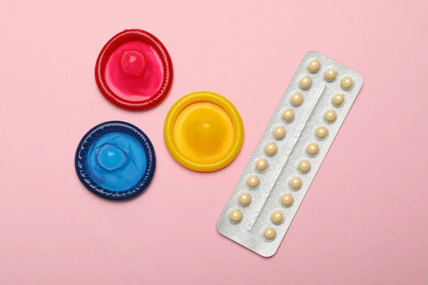 Préservatifs et pilules contraceptives sur fond rose, vue de dessus. Sexe sans risque — Photo