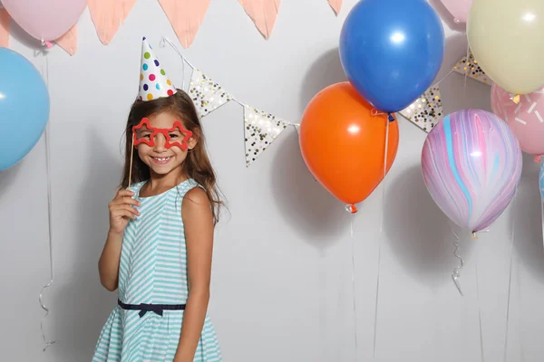 Gelukkig meisje in de buurt heldere ballonnen op verjaardag feest binnen — Stockfoto