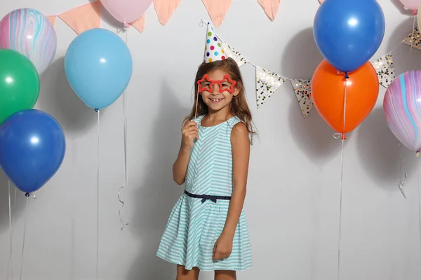 Gelukkig meisje in de buurt heldere ballonnen op verjaardag feest binnen — Stockfoto