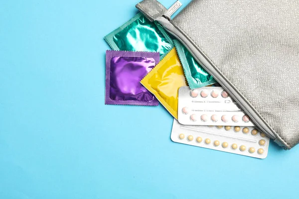 Flat lay composition with birth control pills and condoms on light blue background. Safe sex concept — Φωτογραφία Αρχείου