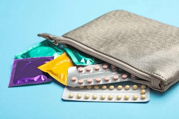 Cosmetic bag with condoms and birth control pills on light blue background. Safe sex concept — Φωτογραφία Αρχείου