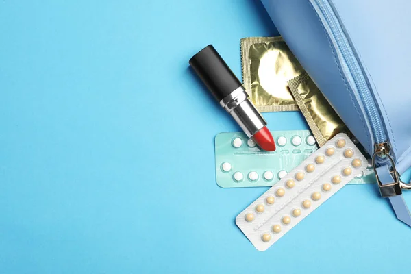 Плоская композиция с противозачаточными таблетками и презервативами на голубом фоне, пространство для текста. Безопасный секс — стоковое фото