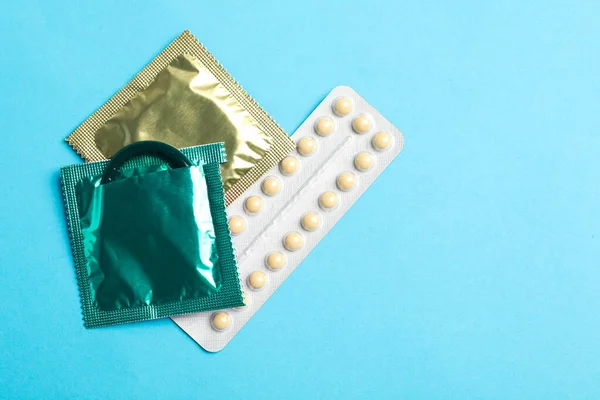 Préservatifs et pilules contraceptives sur fond bleu clair, couché plat avec espace pour le texte. Concept de sexe sûr — Photo