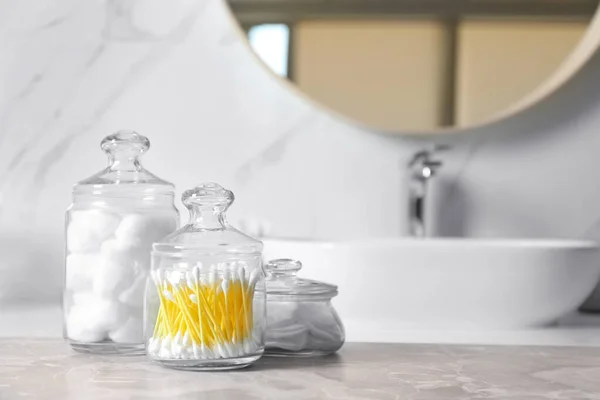 Sfere di cotone, tamponi e tamponi su tavolo in marmo grigio chiaro in bagno — Foto Stock