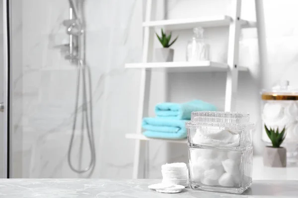 Cuscinetti in cotone e palline su tavolo in marmo grigio chiaro in bagno — Foto Stock