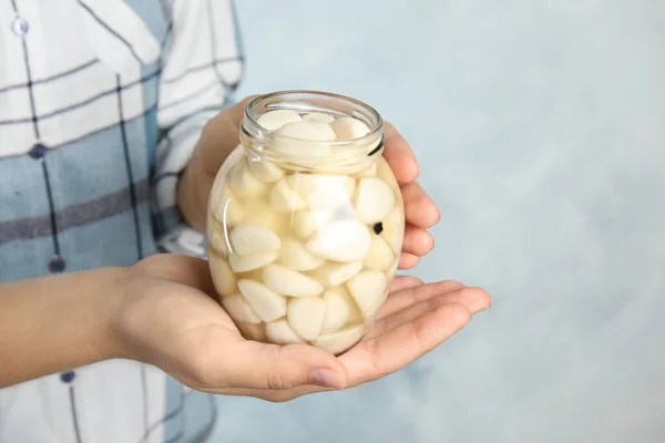 Mujer sosteniendo frasco con ajo en vinagre sobre fondo claro, primer plano — Foto de Stock