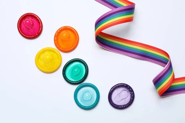 Färgglada kondomer och regnbåge band på vit bakgrund, ovanifrån. Lgbt-konceptet — Stockfoto